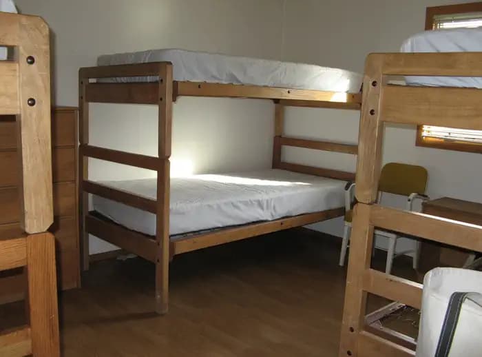 Three sets of twin wooden bunk beds with mattresses in a bedroom