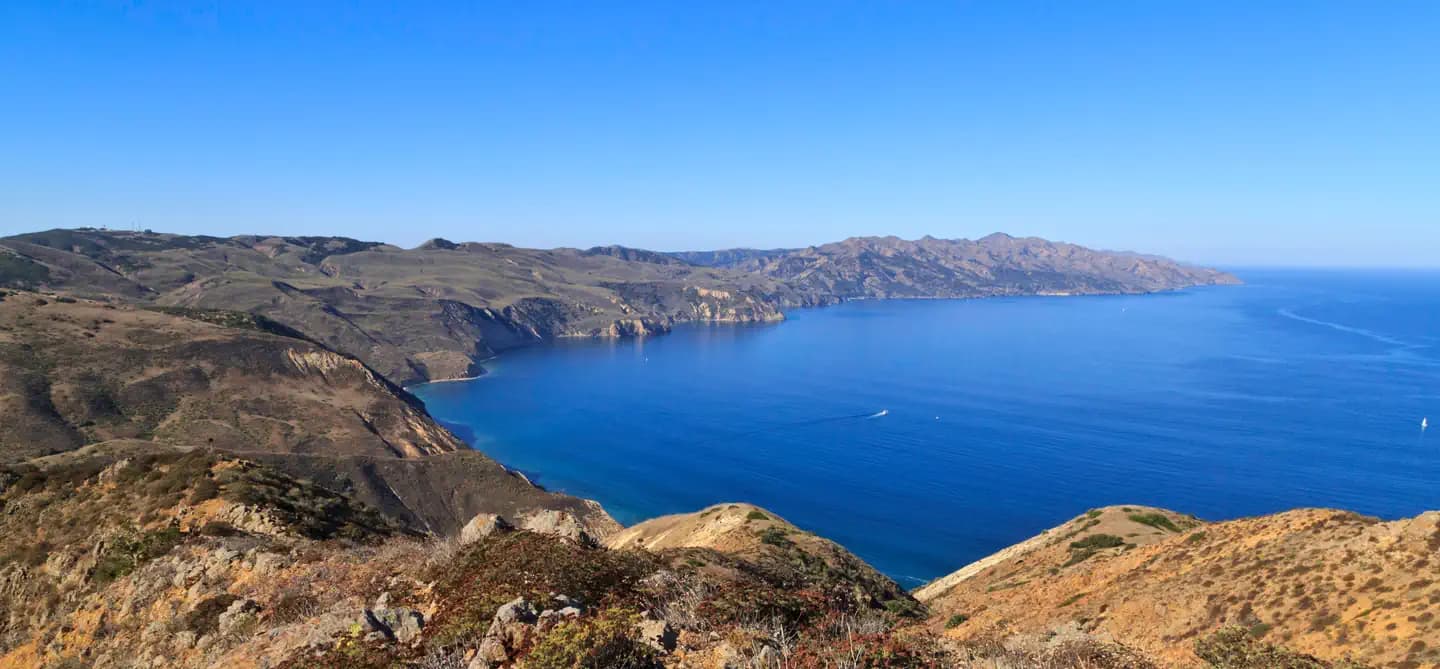 View from a high ridge overlooking the rest of a long, narrow, rugged island with steep cliffs.  