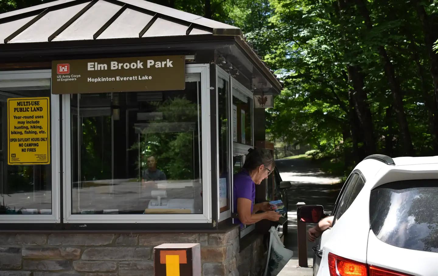 A Park Host greeting a visitor in their vehicle at the Elm Brook Park Entrance Booth.