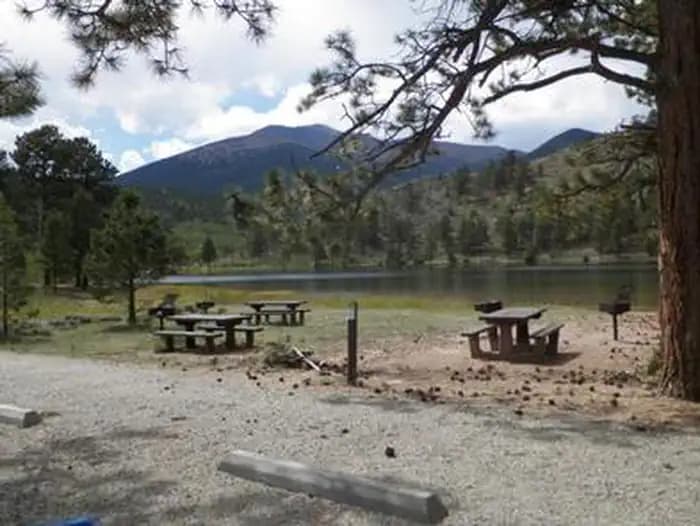Picnic tables near lake with mountains in background