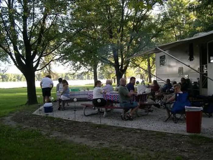 Large Group of people at campsite picnic tables.