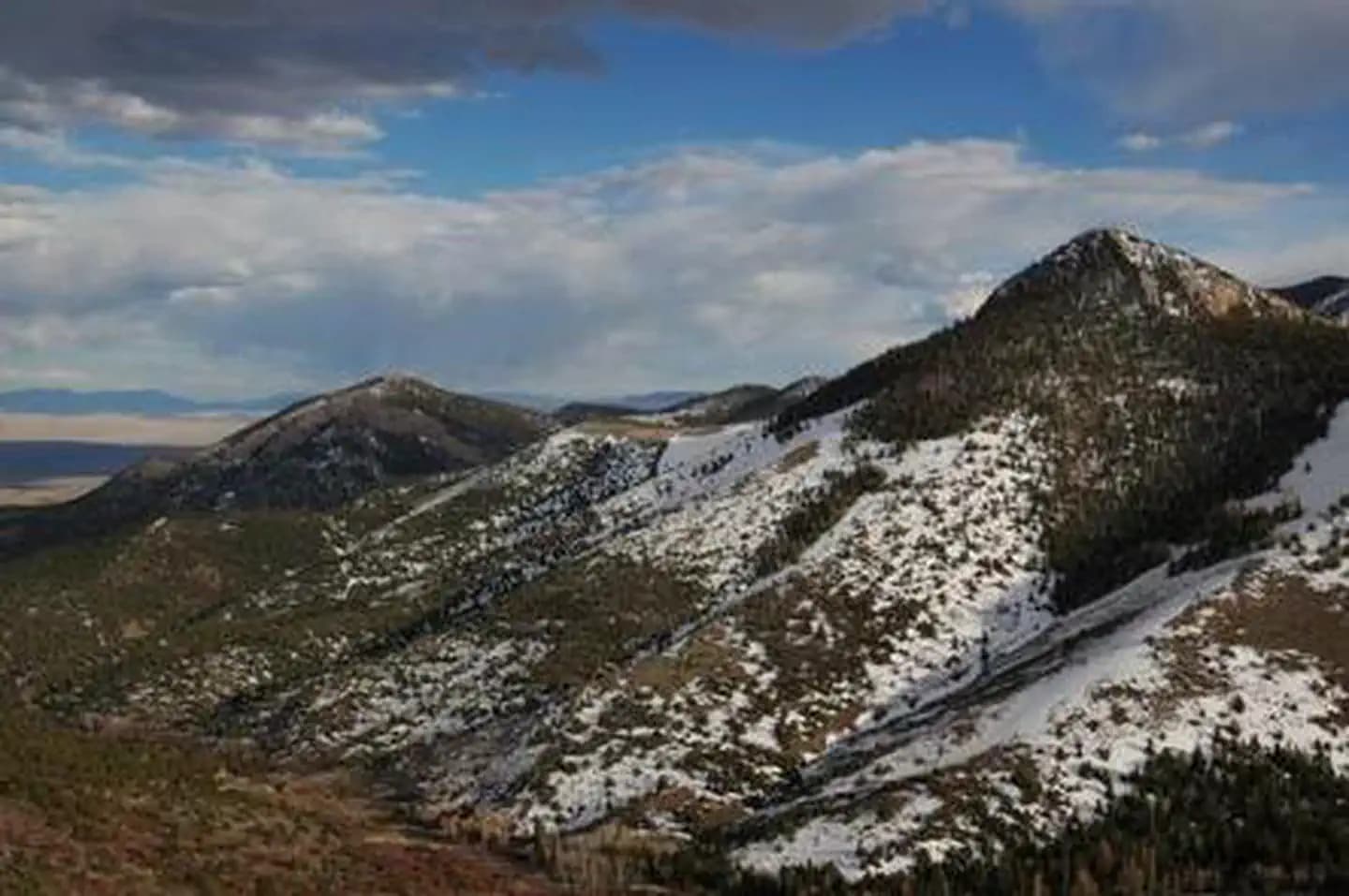 Mountains with patchy snow under blue sky